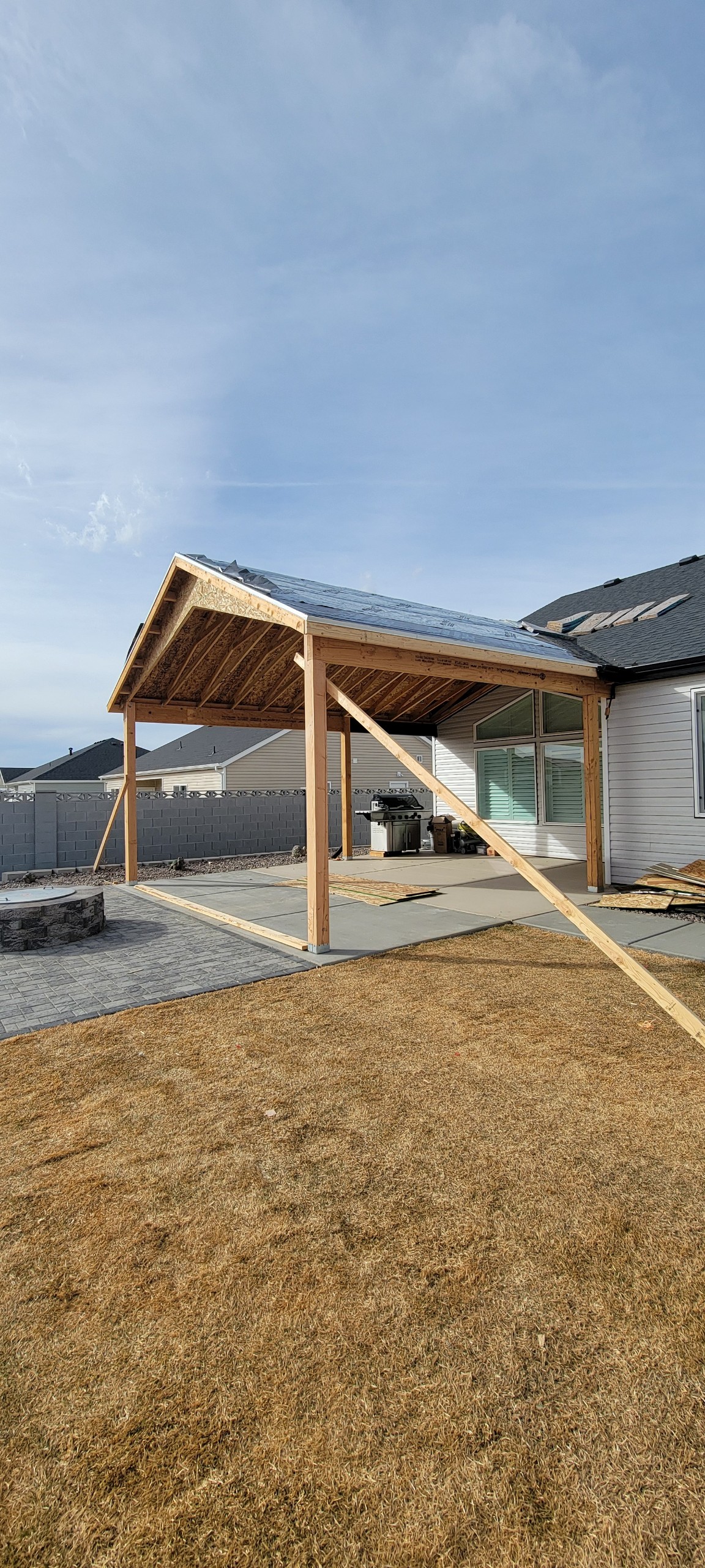 Timber patio cover posts and roof framing beside a home