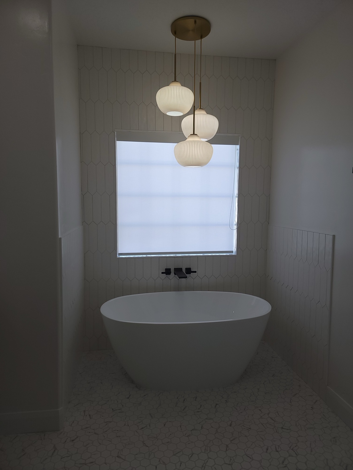 Freestanding soaking tub with tiled walls and pendant lights
